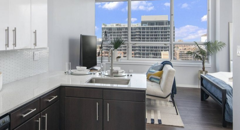 Compact studio kitchen at Arkadia West Loop with contemporary appliances and a bright living/bedroom area