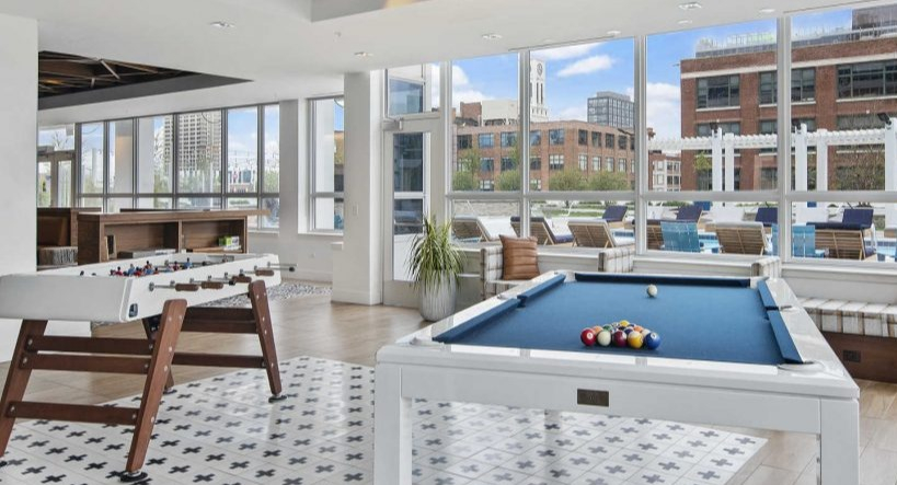 Engaging game room at Arkadia West Loop with a pool table, foosball, and large windows with city views