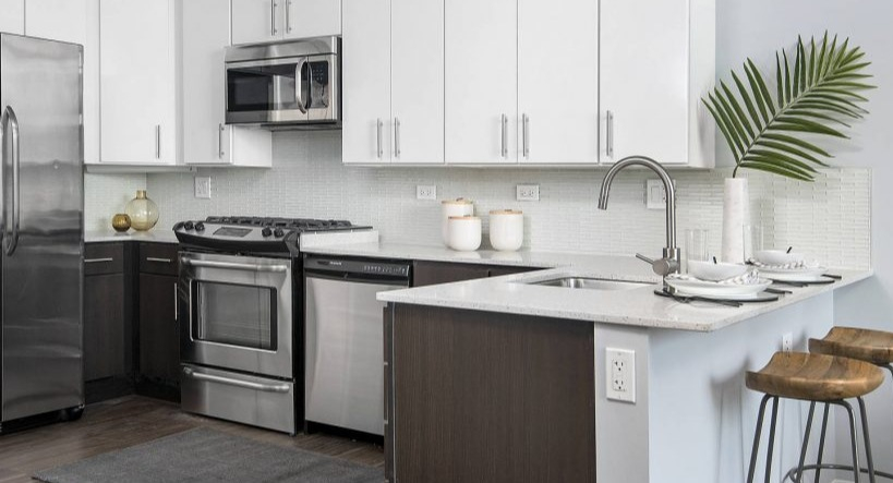 Stylish kitchen at Arkadia West Loop featuring stainless steel appliances, white cabinetry, and a dark island with seating