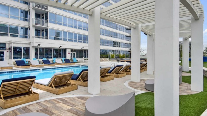 Inviting poolside lounge area with comfortable seating and a pergola, perfect for relaxation at Arkadia West Loop