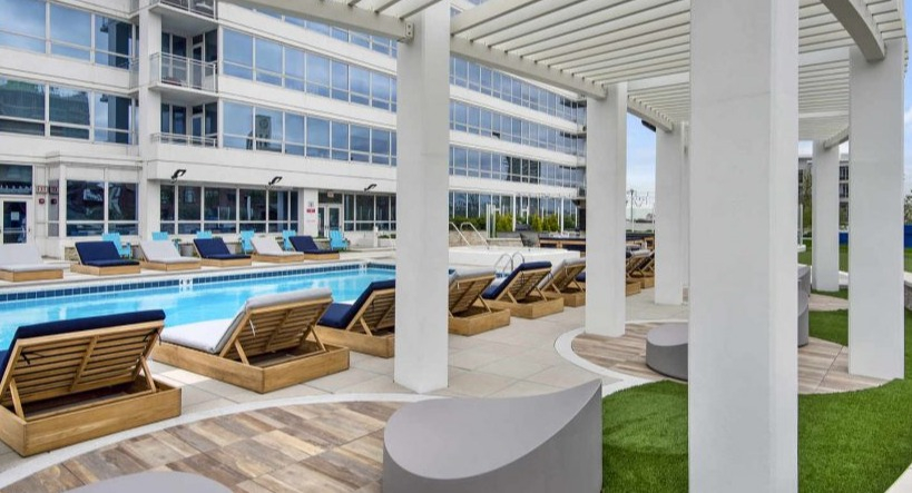 Inviting poolside lounge area with comfortable seating and a pergola, perfect for relaxation at Arkadia West Loop