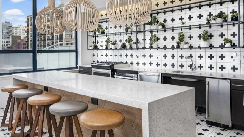 Trendy resident lounge kitchen bar at Arkadia West Loop with unique tiled walls, wooden stools, and pendant lights