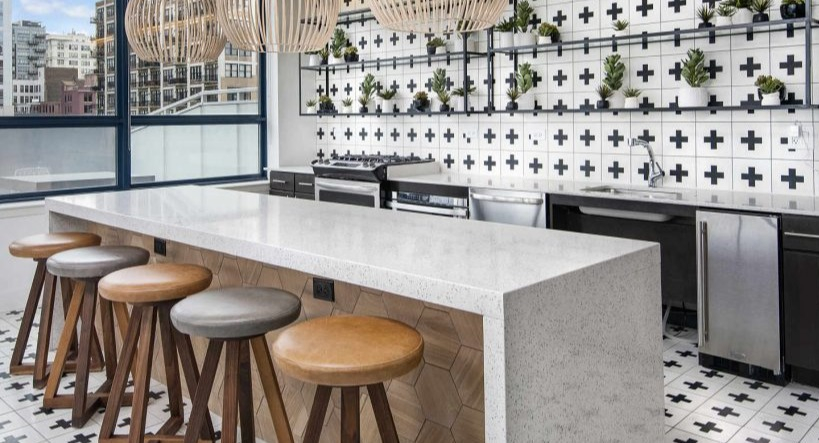 Trendy resident lounge kitchen bar at Arkadia West Loop with unique tiled walls, wooden stools, and pendant lights