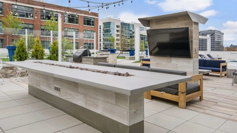 Inviting rooftop lounge at Arkadia West Loop with a long fire pit, comfortable seating, and city views