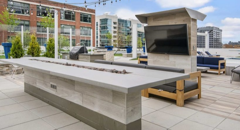 Inviting rooftop lounge at Arkadia West Loop with a long fire pit, comfortable seating, and city views