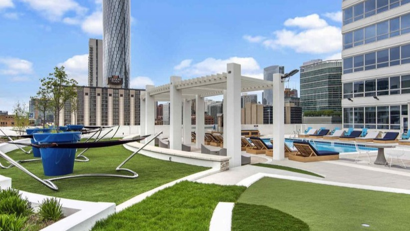 Panoramic view of Arkadia West Loop's rooftop lounge with hammocks, lush green spaces, and city skyline