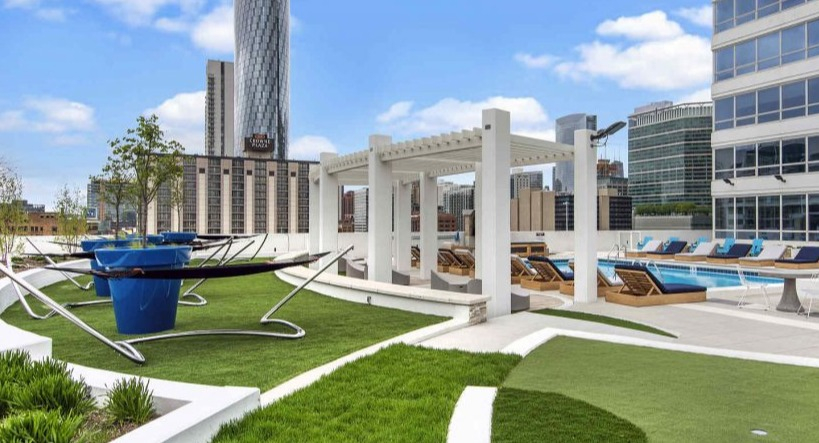 Panoramic view of Arkadia West Loop's rooftop lounge with hammocks, lush green spaces, and city skyline