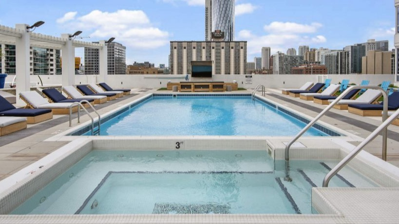 Stunning rooftop pool and hot tub with lounge chairs, offering city views at Arkadia West Loop