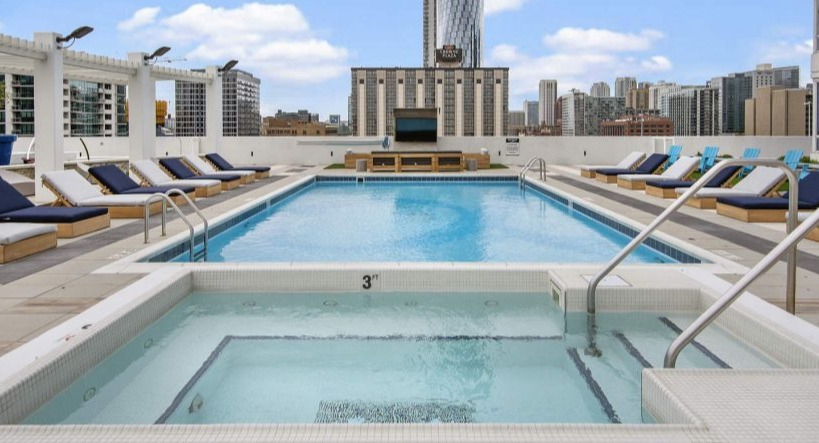 Stunning rooftop pool and hot tub with lounge chairs, offering city views at Arkadia West Loop