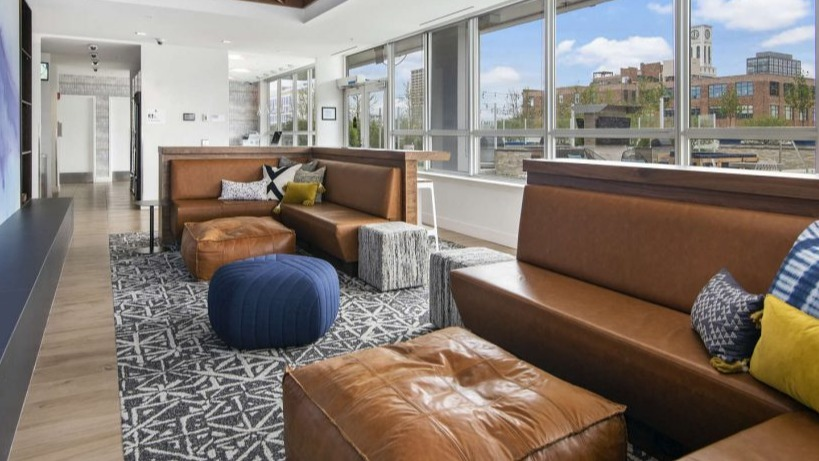 Comfortable tenant lounge at Arkadia West Loop with plush leather seating, ottomans, and a unique ceiling design