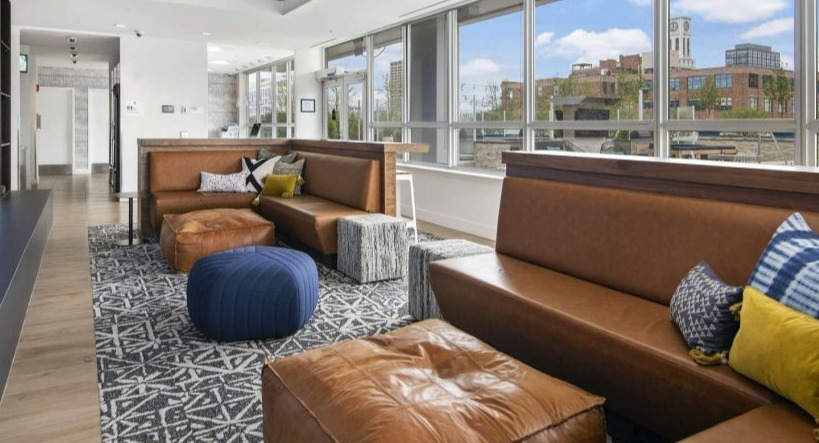 Comfortable tenant lounge at Arkadia West Loop with plush leather seating, ottomans, and a unique ceiling design