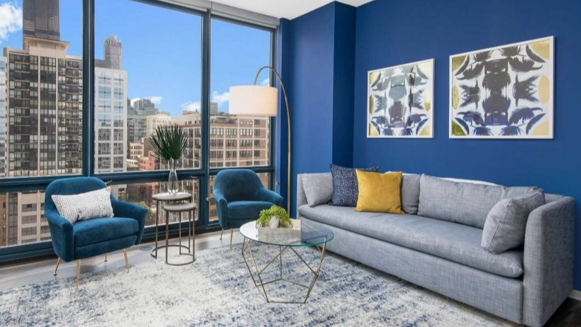Vibrant living area at Arkadia West Loop featuring blue accents, stylish furniture, and expansive city views