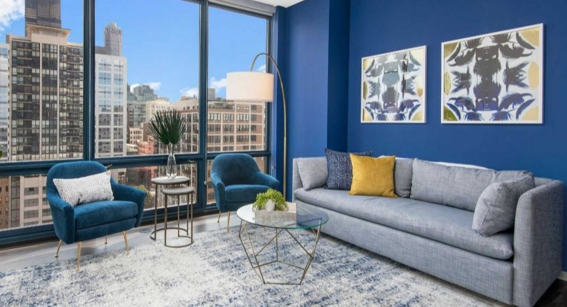 Vibrant living area at Arkadia West Loop featuring blue accents, stylish furniture, and expansive city views