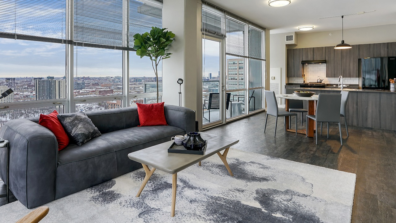 Bright living room and kitchen combo with expansive city views, modern decor, and comfortable seating at Arrive LEX in Chicago
