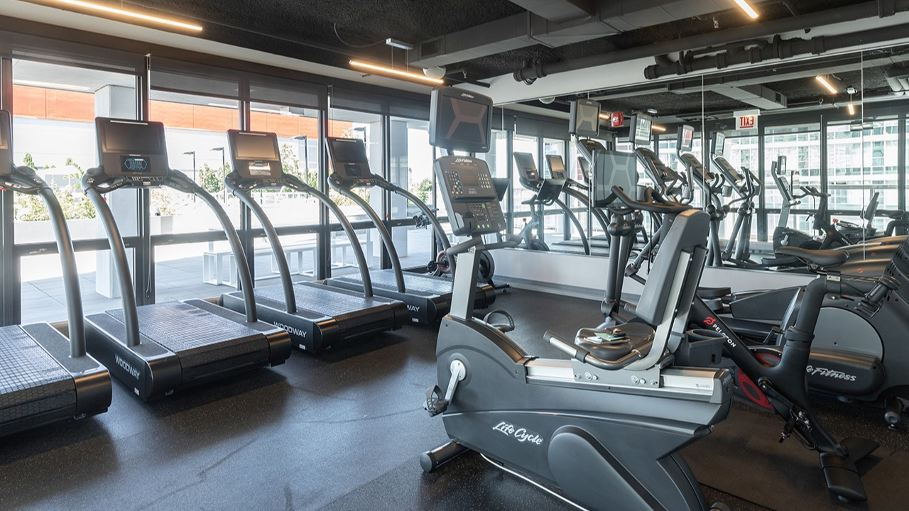 Well-equipped fitness center with treadmills, exercise bikes, and large mirrors, providing a great workout space at Arrive LEX in Chicago