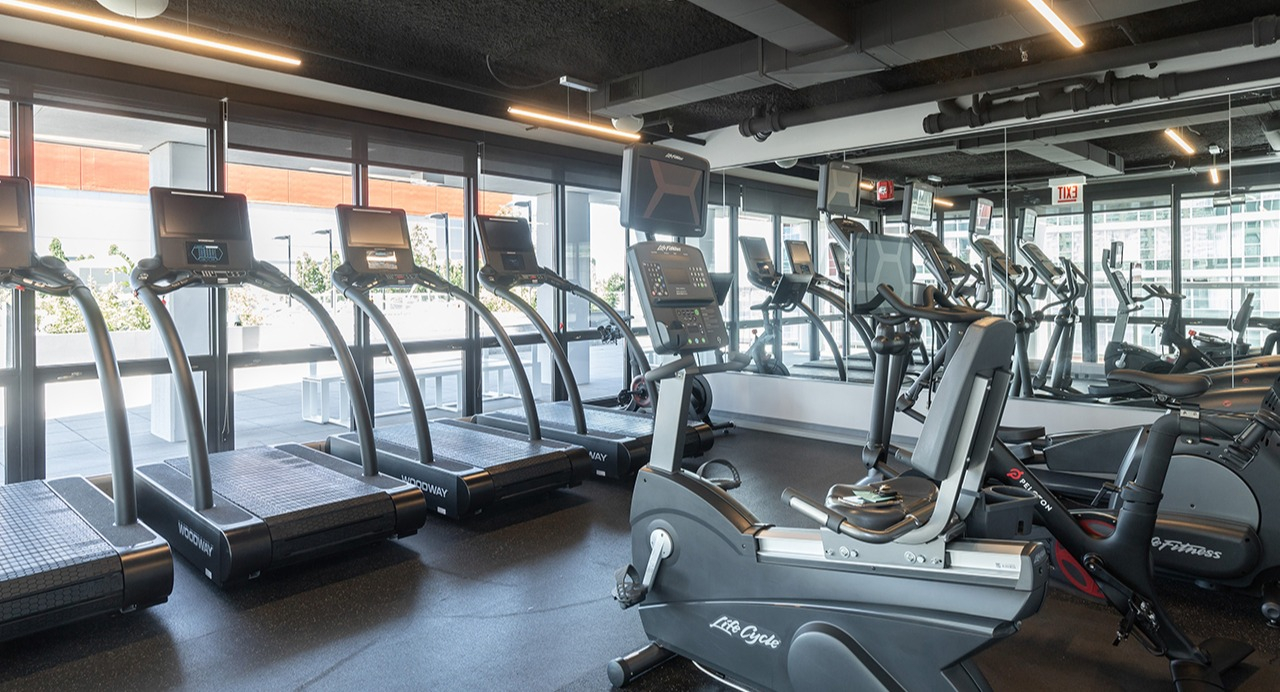 Well-equipped fitness center with treadmills, exercise bikes, and large mirrors, providing a great workout space at Arrive LEX in Chicago