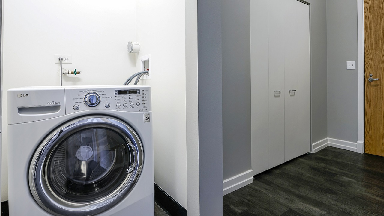 Convenient in-unit laundry room with a front-loading washing machine, ample space, and a clean, modern design at Arrive LEX in Chicago