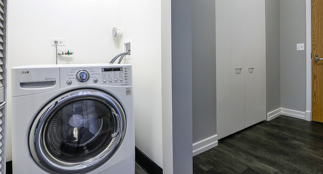 Convenient in-unit laundry room with a front-loading washing machine, ample space, and a clean, modern design at Arrive LEX in Chicago