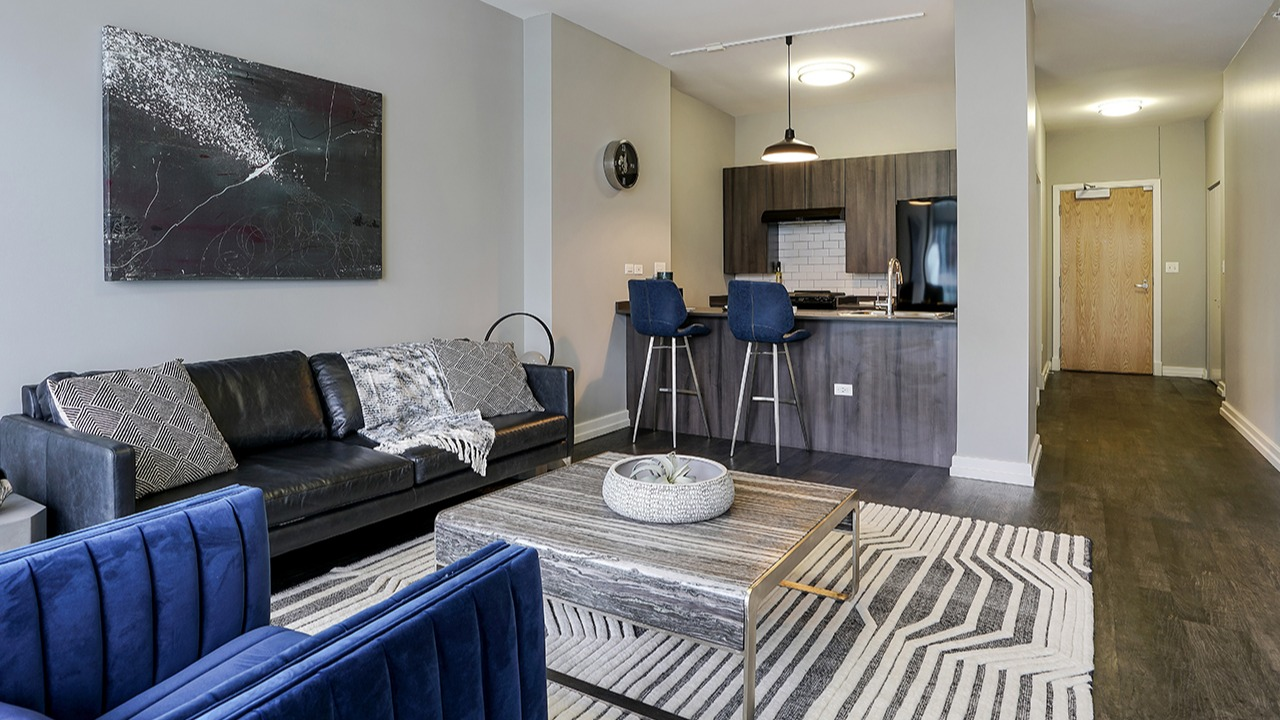 Open-layout living room and kitchen area with modern furnishings, a comfortable couch, and a breakfast bar at Arrive LEX in Chicago