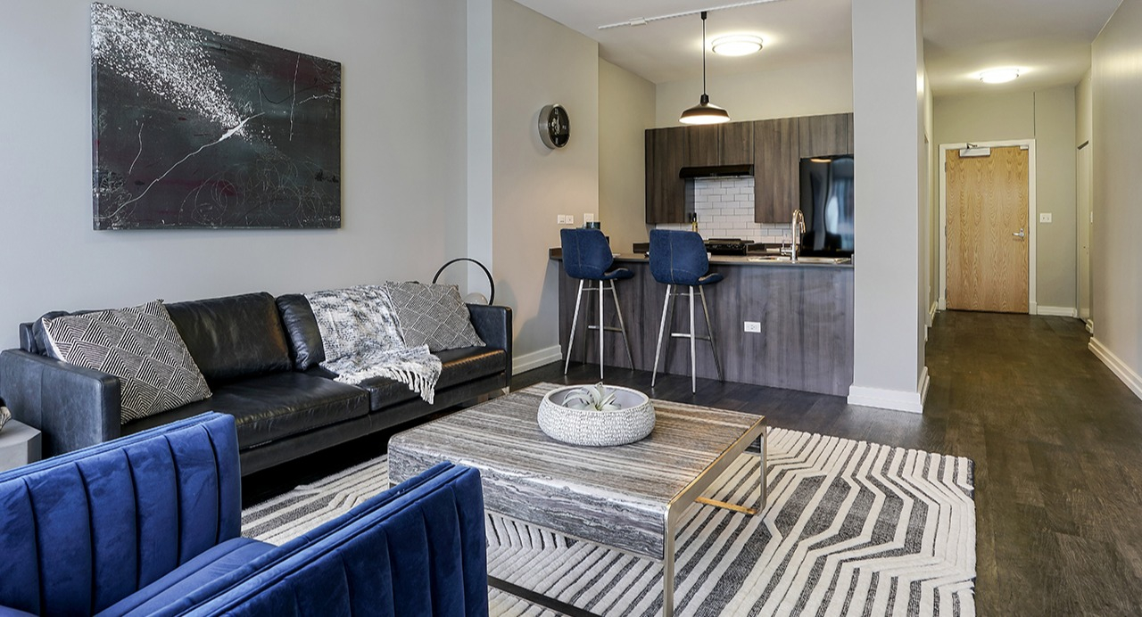 Open-layout living room and kitchen area with modern furnishings, a comfortable couch, and a breakfast bar at Arrive LEX in Chicago