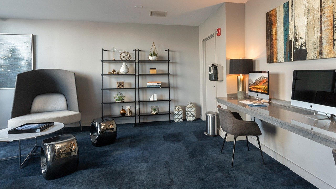 Resident computer lounge with multiple workstations, modern shelving, comfortable seating, and stylish artwork at Arrive LEX in Chicago