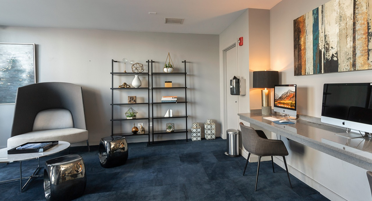 Resident computer lounge with multiple workstations, modern shelving, comfortable seating, and stylish artwork at Arrive LEX in Chicago