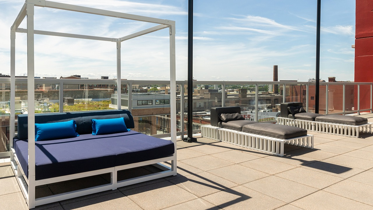 Spacious rooftop lounge area with modern daybeds and chaise lounges, perfect for sunbathing and relaxation at Arrive LEX in Chicago