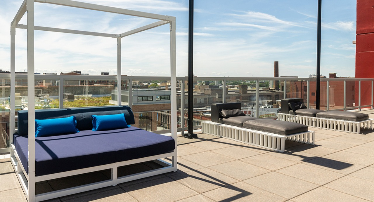 Spacious rooftop lounge area with modern daybeds and chaise lounges, perfect for sunbathing and relaxation at Arrive LEX in Chicago