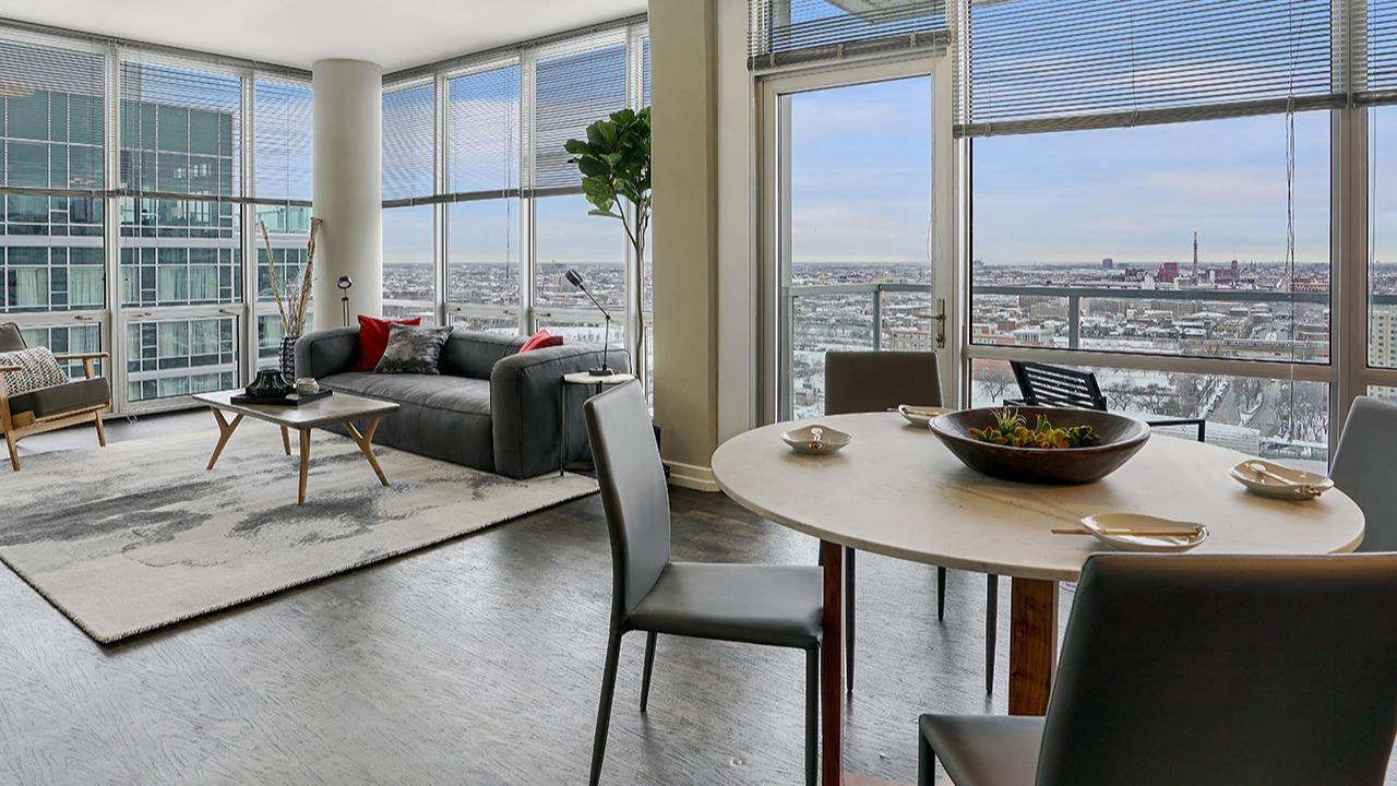 Spacious living and dining area with floor-to-ceiling windows, city views, modern furniture, and an open-concept layout at Arrive LEX in Chicago