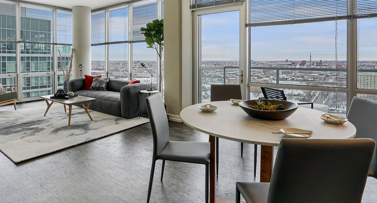 Spacious living and dining area with floor-to-ceiling windows, city views, modern furniture, and an open-concept layout at Arrive LEX in Chicago