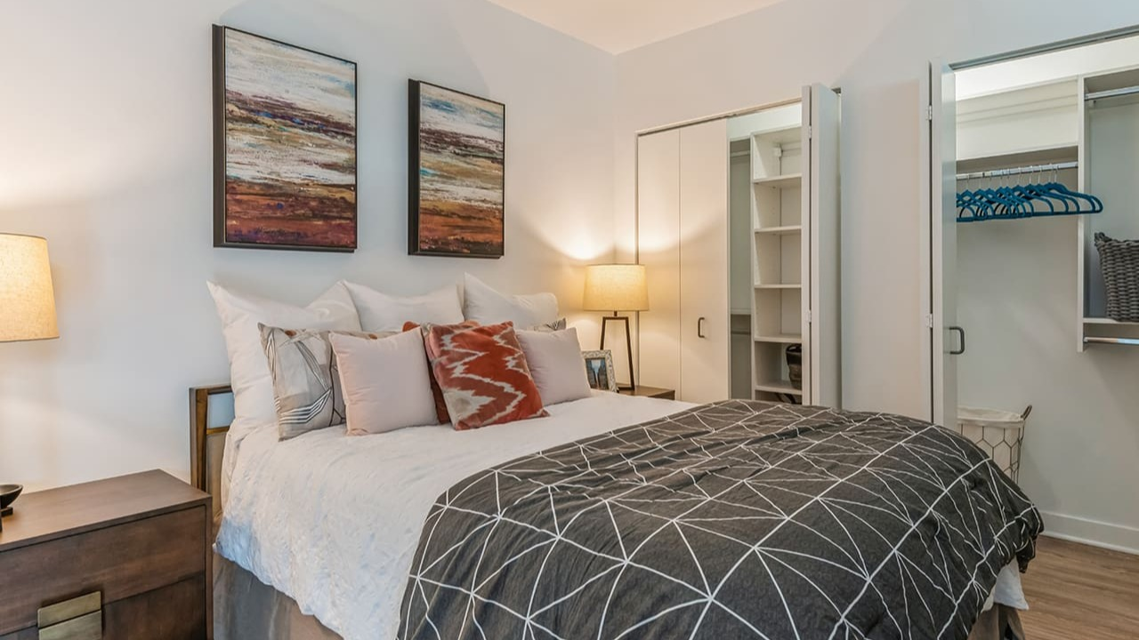 A cozy bedroom with a comfortable bed, warm lighting, and a spacious walk-in closet at Arrive Michigan Avenue apartments in Chicago