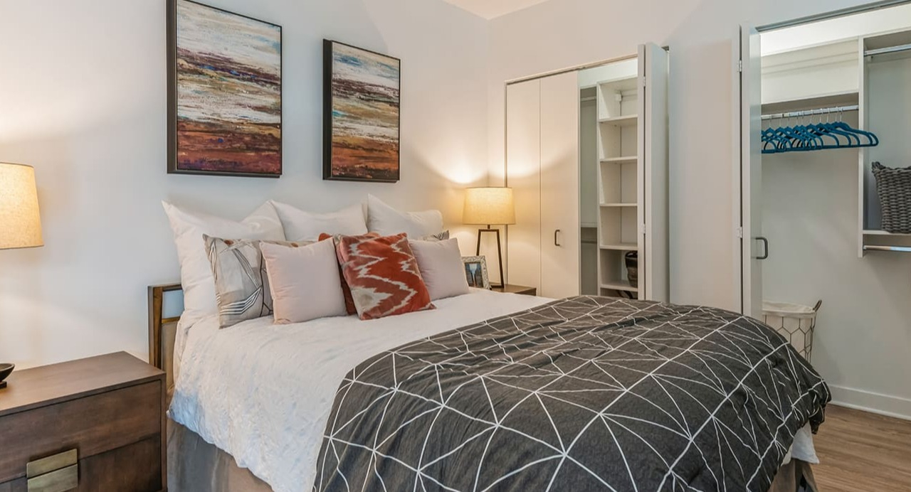 A cozy bedroom with a comfortable bed, warm lighting, and a spacious walk-in closet at Arrive Michigan Avenue apartments in Chicago