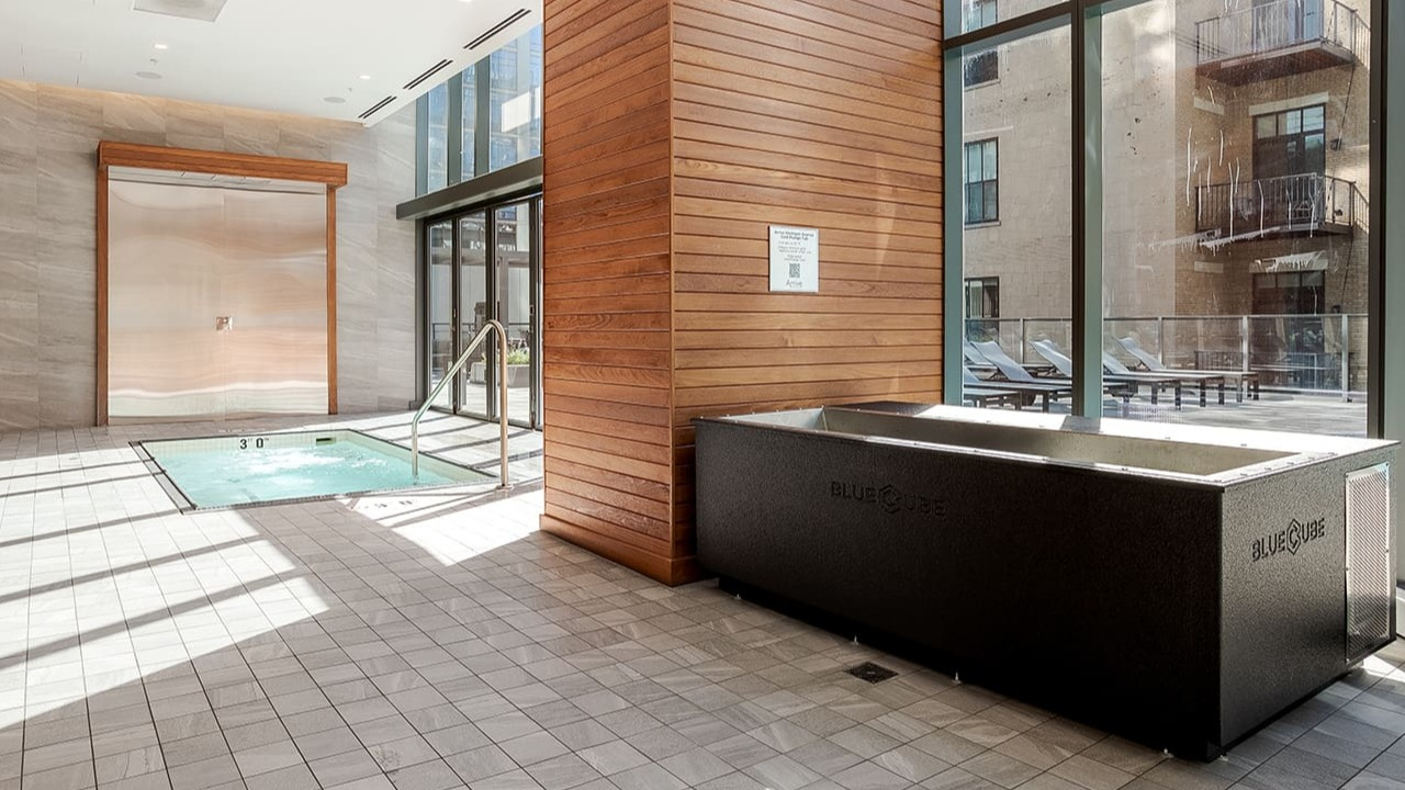 Indoor pool and spa area with a cold plunge pool and large windows at Arrive Michigan Avenue apartments in Chicago