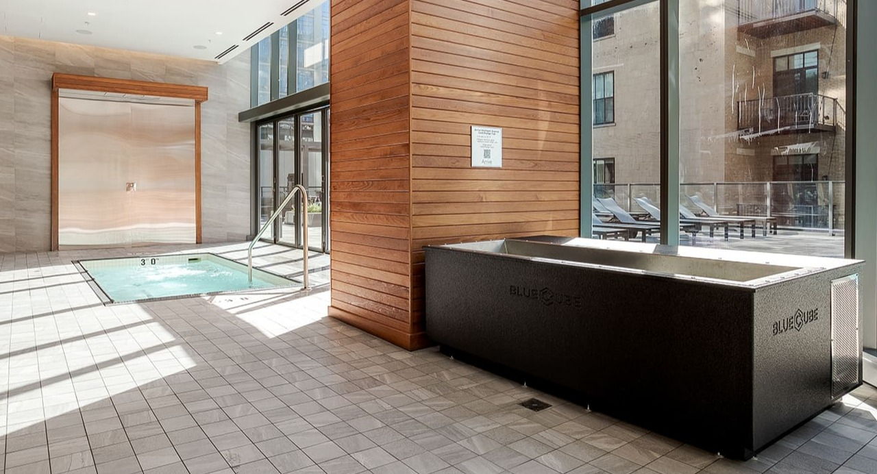 Indoor pool and spa area with a cold plunge pool and large windows at Arrive Michigan Avenue apartments in Chicago