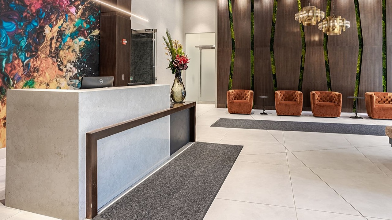 A luxurious and modern apartment lobby with a reception desk and vibrant artwork at Arrive Michigan Avenue in Chicago