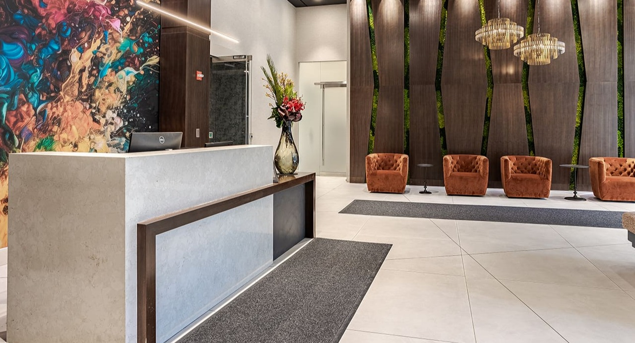 A luxurious and modern apartment lobby with a reception desk and vibrant artwork at Arrive Michigan Avenue in Chicago