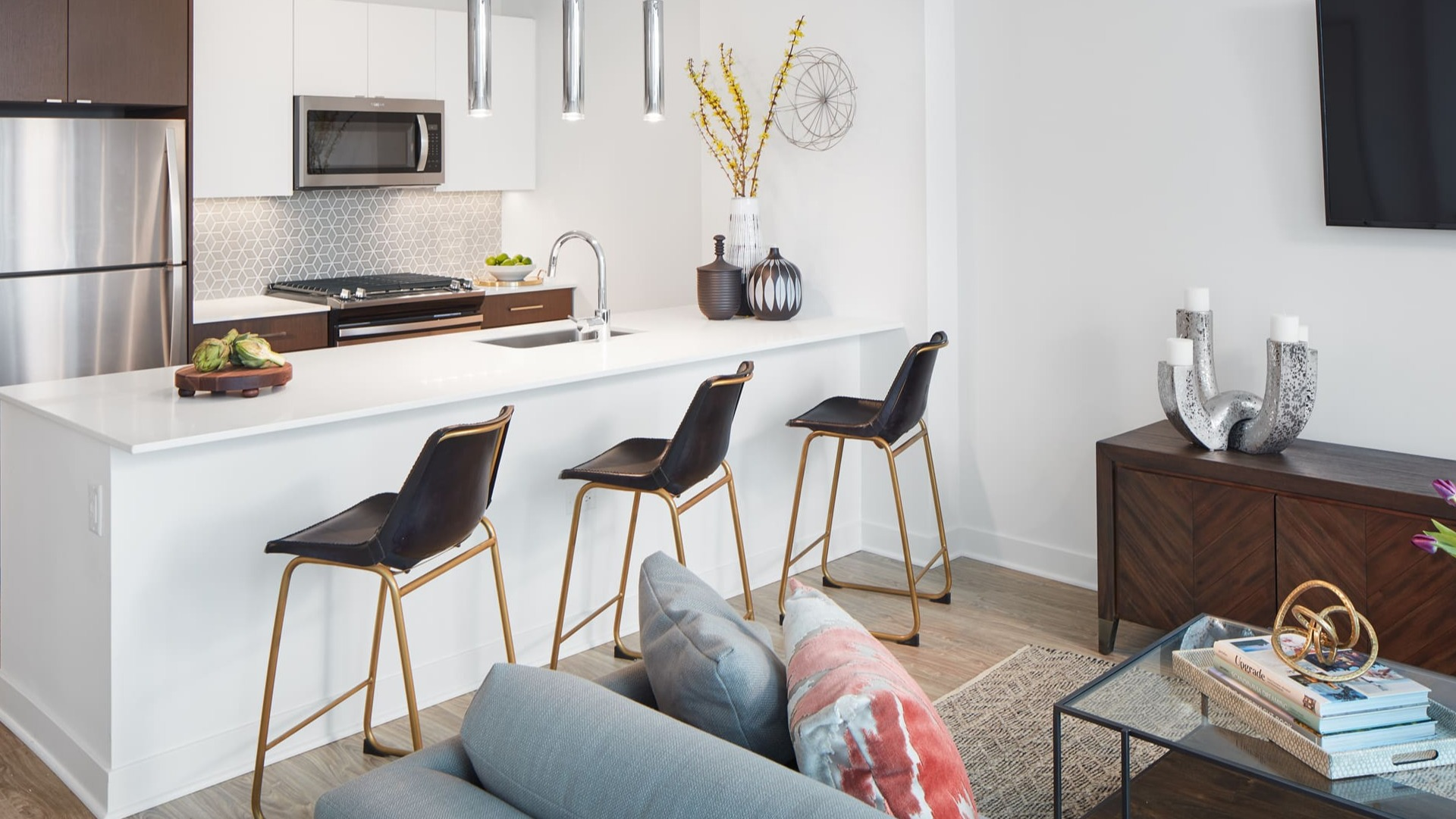 Modern open-concept kitchen with white countertops, stainless steel appliances, and a breakfast bar at Arrive Michigan Avenue in Chicago