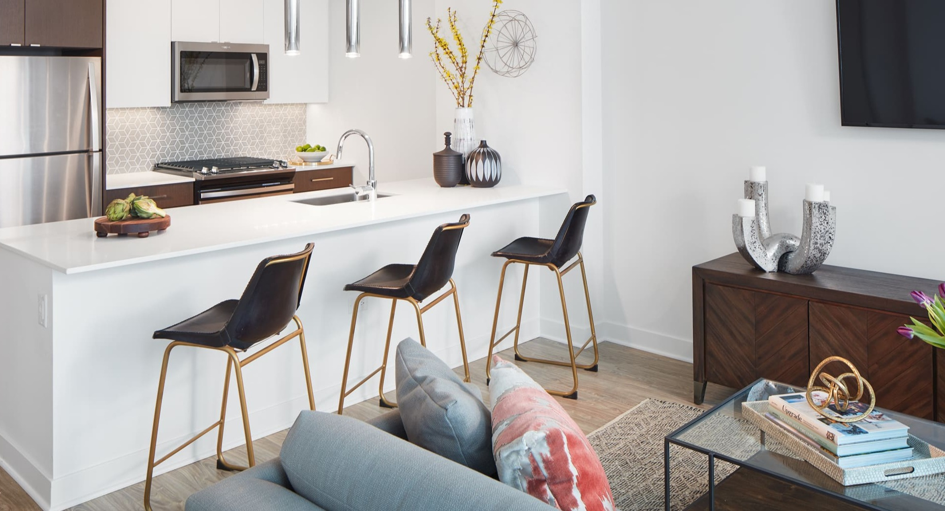 Modern open-concept kitchen with white countertops, stainless steel appliances, and a breakfast bar at Arrive Michigan Avenue in Chicago