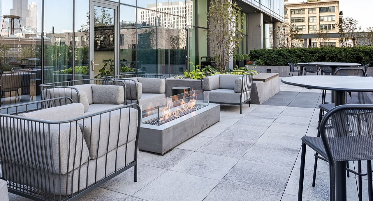 Outdoor patio with a modern fire pit, comfortable seating, and city views at Arrive Michigan Avenue apartments in Chicago