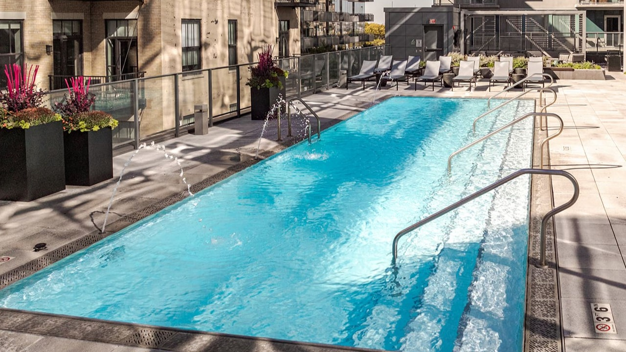 Inviting rooftop swimming pool with lounge chairs and cityscape views at Arrive Michigan Avenue apartments in Chicago