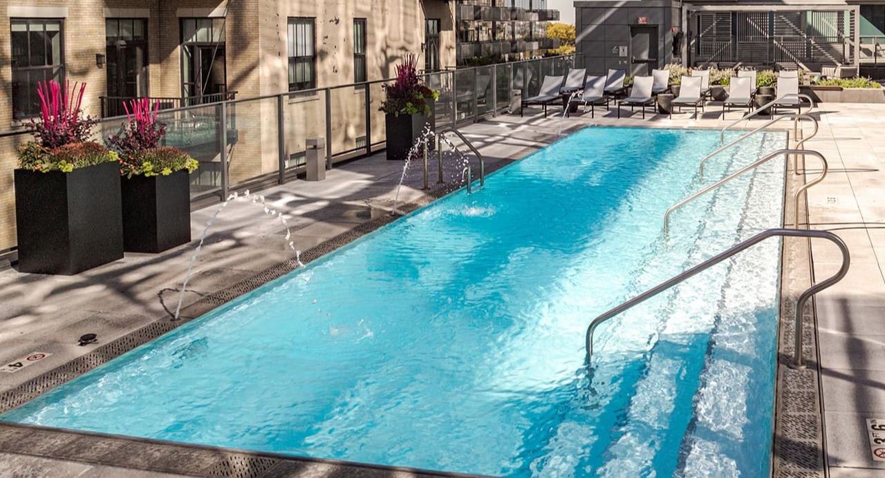 Inviting rooftop swimming pool with lounge chairs and cityscape views at Arrive Michigan Avenue apartments in Chicago