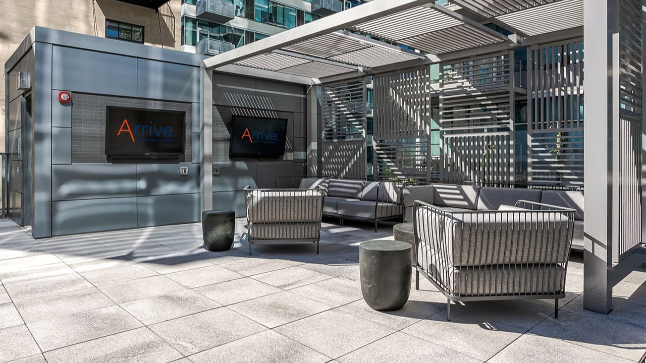 Shaded outdoor lounge area with comfortable seating and televisions, perfect for relaxation at Arrive Michigan Avenue in Chicago