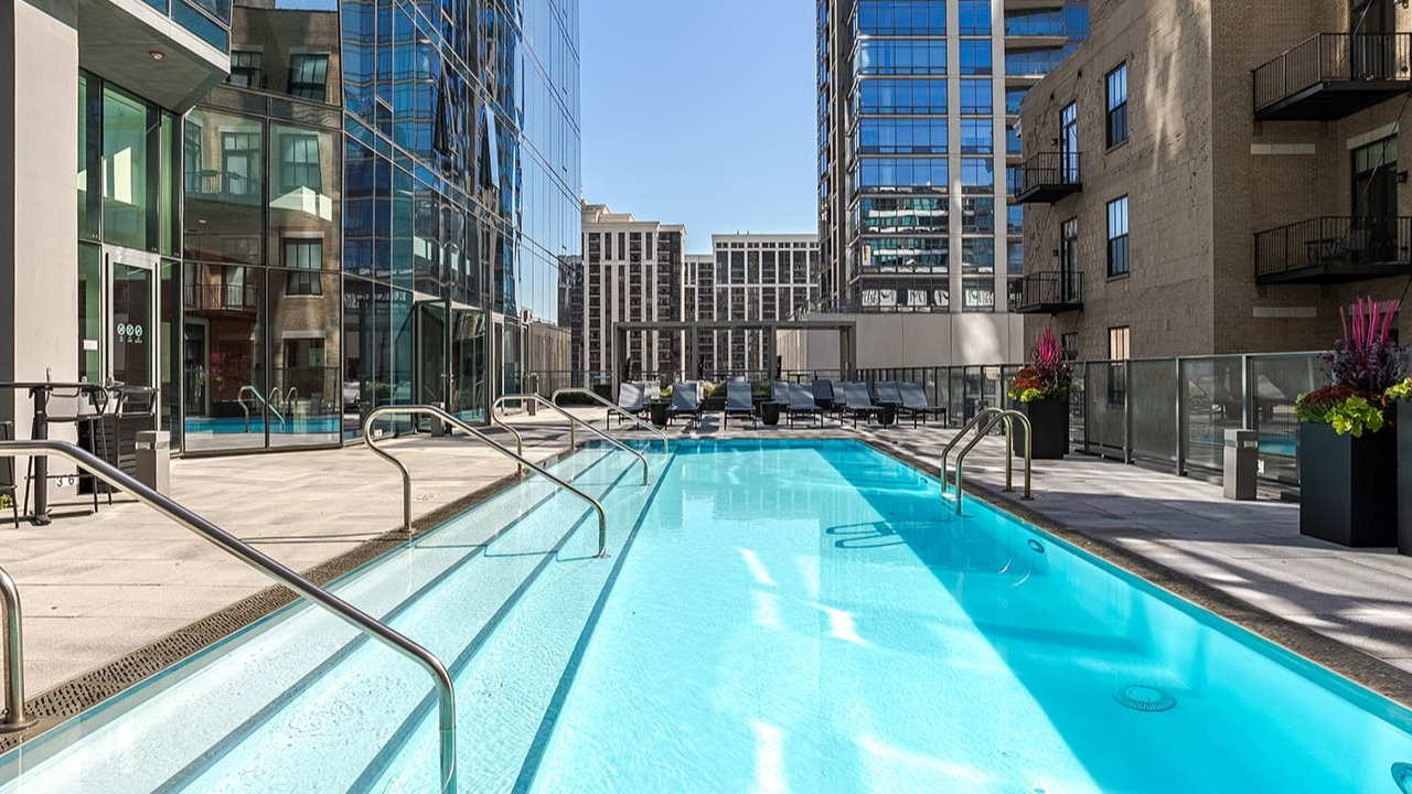 A sleek outdoor swimming pool surrounded by modern buildings under a clear sky at Arrive Michigan Avenue in Chicago