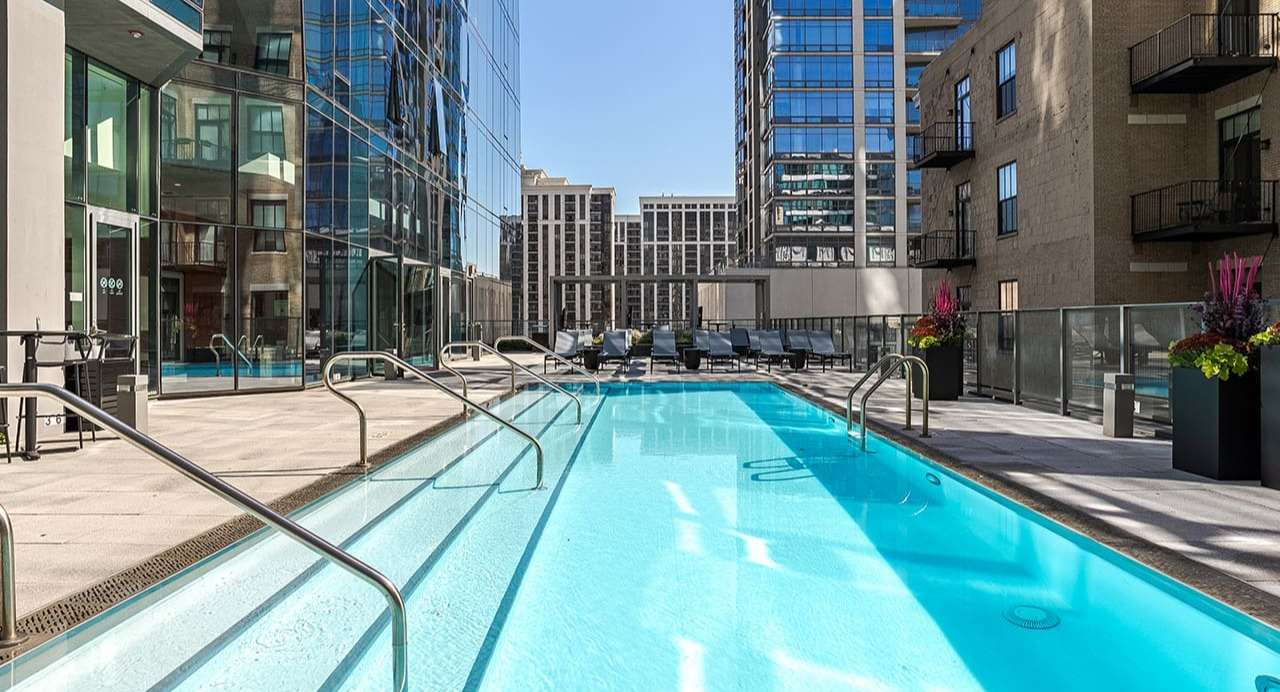 A sleek outdoor swimming pool surrounded by modern buildings under a clear sky at Arrive Michigan Avenue in Chicago