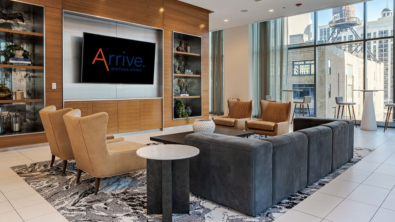 Chic resident lounge with a large TV, ample seating, and stylish shelving at Arrive Michigan Avenue apartments in Chicago
