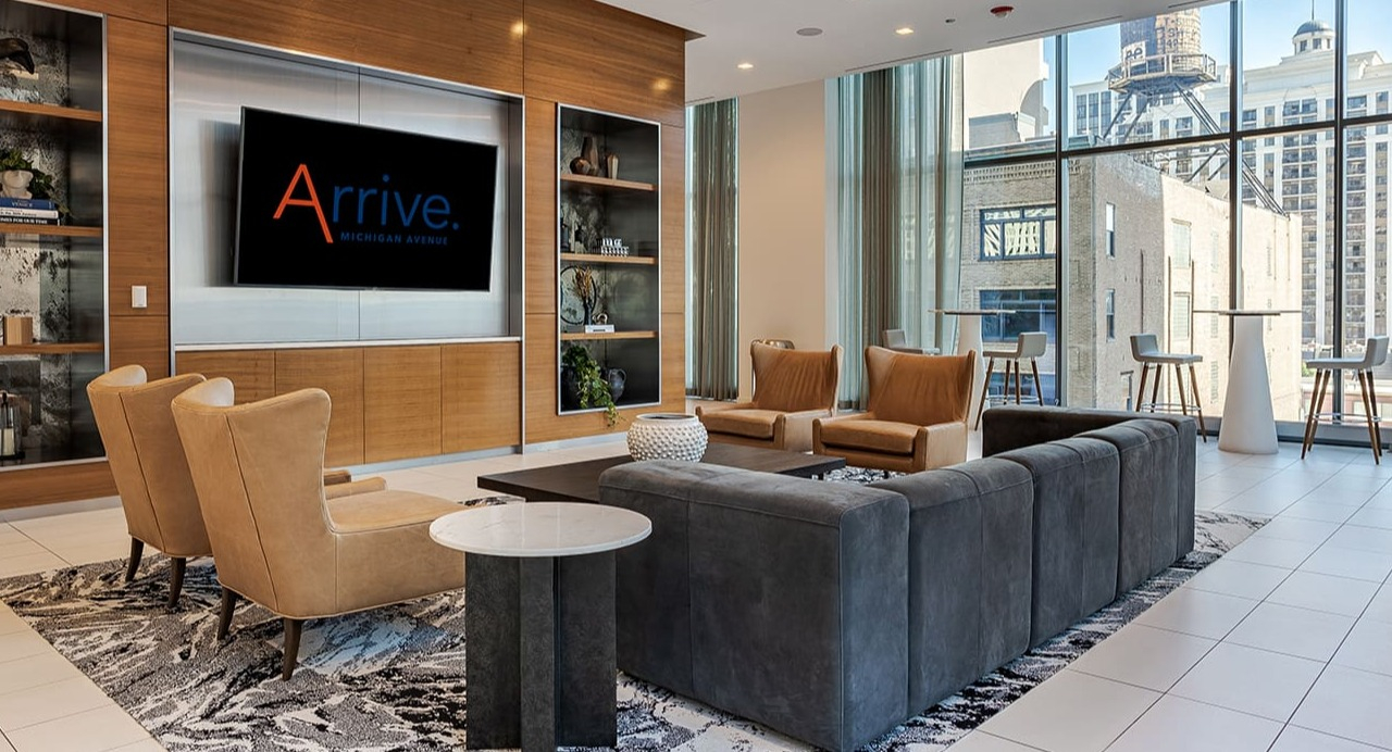 Chic resident lounge with a large TV, ample seating, and stylish shelving at Arrive Michigan Avenue apartments in Chicago