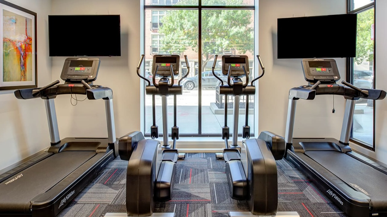 Cardio area in the fitness center at Arrive South Loop apartments, featuring treadmills and ellipticals with individual screens in Chicago
