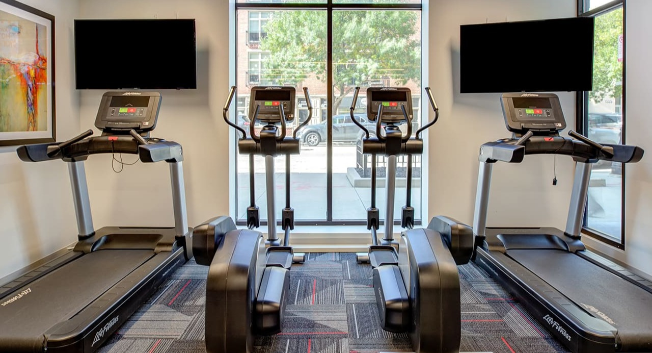 Cardio area in the fitness center at Arrive South Loop apartments, featuring treadmills and ellipticals with individual screens in Chicago