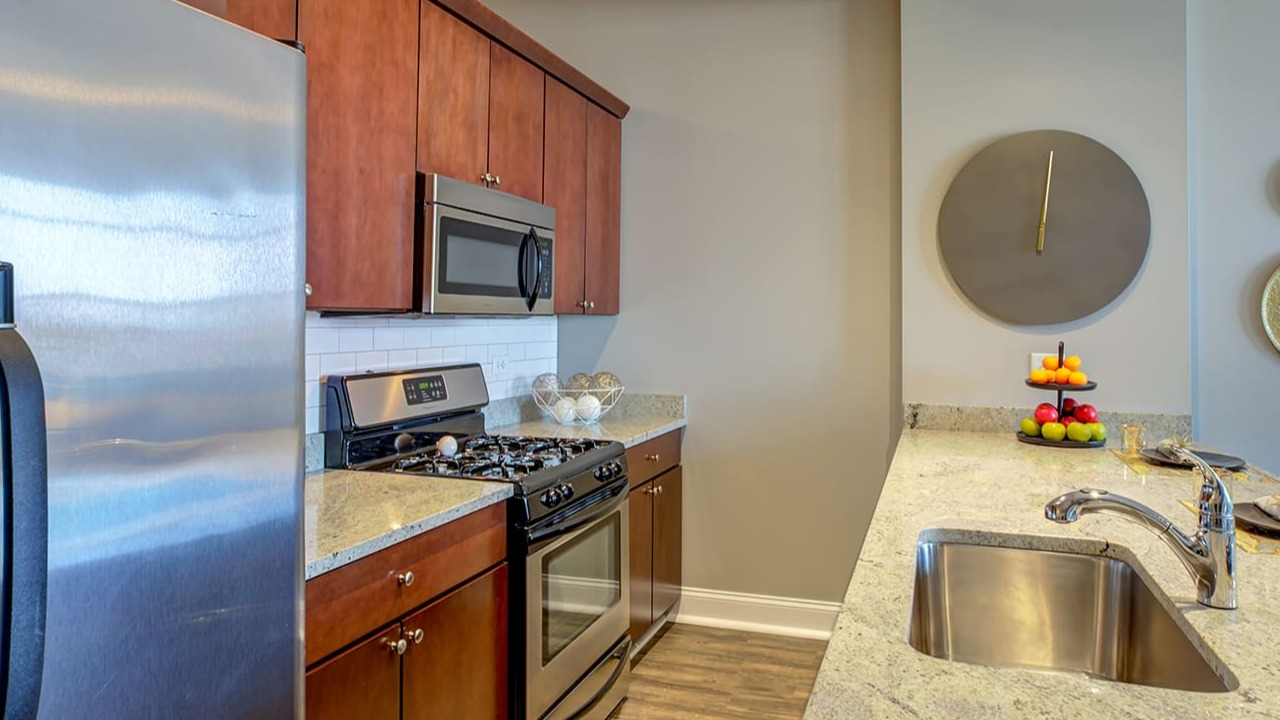 Detailed view of a kitchen at Arrive South Loop, showcasing granite countertops, stainless steel appliances, and ample cabinet space in Chicago