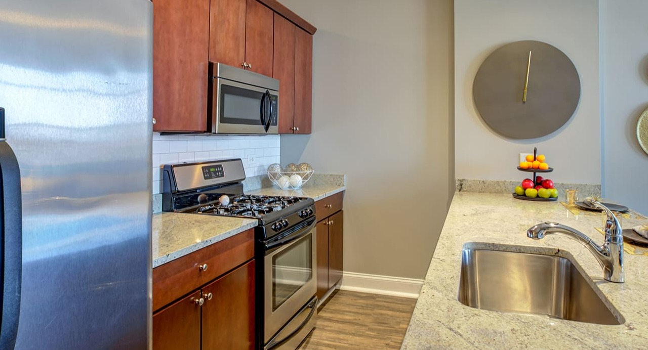 Detailed view of a kitchen at Arrive South Loop, showcasing granite countertops, stainless steel appliances, and ample cabinet space in Chicago